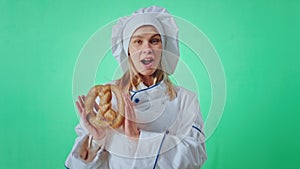 Large smile baker woman with a French pretzel dancing in front of the camera excited she make funny face in a green big