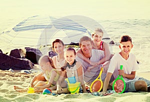 Large smiling family of six people together on beach