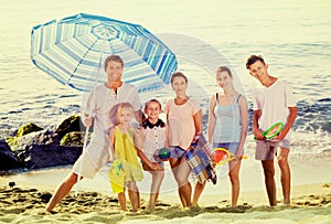 Large smiling family standing together on beach on summer day