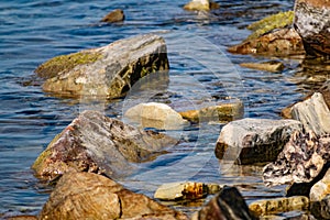 Large and smooth stones in the coastal waves of salty sea water. The coast of the black sea foams and roars