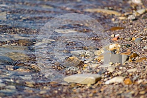 Large and smooth stones in the coastal waves of salty sea water. The coast of the black sea foams and roars, beating against a hug