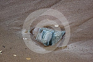 Large and smooth stones in the coastal waves of salty sea water. The coast of the black sea foams and roars, beating against a hug