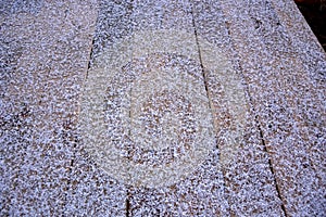 Large snow is lying on the wooden surface. Anomalous phenomenon.