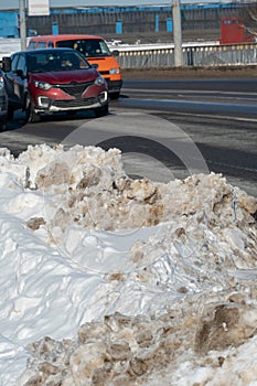 Large snowdrifts on the roadsides after snow removal by special equipment. Cleared roads of snow and ice. Safe driving in winter