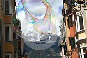 A large soap bubble with rainbow colors floats in the sky.