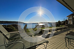 Large spacious deck of grey waterfront home at sunset