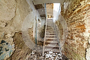 Large spacious forsaken empty basement passageway of ancient building or palace with cracked plastered brick walls and narrow photo