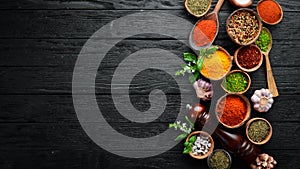 Large spice and herb collection in bowls and spoons. Indian spices. On a black wooden background.