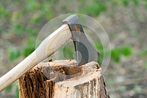 Large splitting axe with sharp metal head and wooden handle in stump on natural landscape outdoors, tool