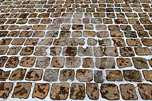 Large square paving stones made of natural granite are covered with snow in winter