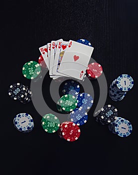 Large stack of different chips and the highest combination of playing cards in poker - royal flush isolated over black casino