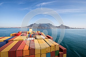 Large stacked container ship leaving the port of Cape Town with Table mountain and the city in the background, South Africa.