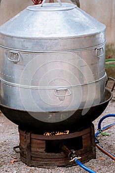 Large steamer, cooking equipment. Hot steamer pot and boiling water on charcoal stove or brazier. Traditional silver steamer pot