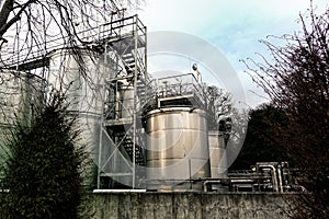 Large steel industrial vats or containers for gas or chemicals, with walkways and gantries, in rural setting.
