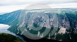 Large steep cliffs and plateau forming fjord under overcast sky