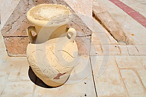 Large stone, clay-old antique vintage yellow carved heavy pitcher with patterns on the stone floor