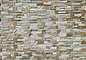 Large stone coating wall made of bricks and cubes of multicolor rocks.