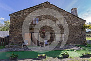 Large stone house with several windows and several chairs on the terrace at sunset on a summer day. photo