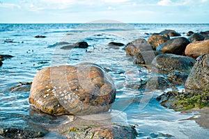 Large stone in the water on the beach in the sea. Danish coast on a sunny day