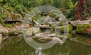 Large stones by the lake in the forest in Sofievka park in Uman