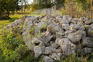 Large stones lie in a large pile on the grass. Beautiful large stones stacked in the grass. Rock stones are dumped into
