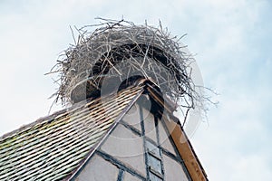 Large stork nest on the roof gable of a traditional wooden half-timbered house in the Alsace region of France