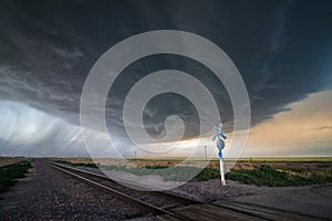 A large storm blows in over a railroad crossing, producing heavy rain and extreme winds.