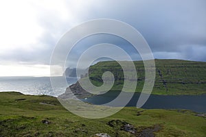 Large storm clouds gather over the picturesque cliffs and ocean in Faroe Islands