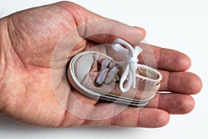 In a large and strong male hand is a small children`s shoes. On shoes tied with a bow bow. photo
