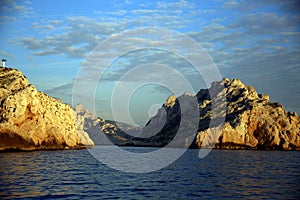 Large sunny rocks in the blue of the Mediterranean sea, with the coast in the background, Parc National des Calanques, Marseille,