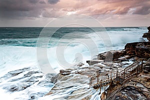 Large swells engulf the rock shelf  at sunset