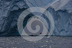 Old eroded tabular iceberg with zodiac and expedition group, Antarctica photo