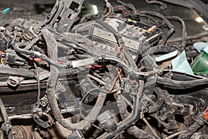 A large tangle of ravel multicolored wires from the car wiring lies in the cabin of the dismantled car with connectors and plugs,