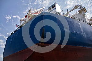 A large tanker cargo ship is being renovated and painted in shipyard dry dock