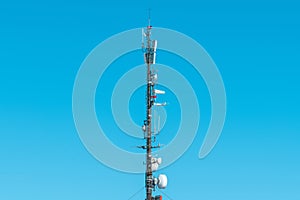 Large telecommunication tower with antennas and satellite dishes, mobile telephony signal repeaters and 4g transmitters and