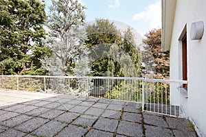 Large terrace in country house with with stone tiled floor, big trees view