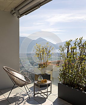 Large terrace of a house in Switzerland with a view of Lake Maggiore. Sunny day and a cosy armchair with cushion