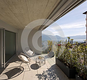 Large terrace of a house in Switzerland with a view of Lake Maggiore. Sunny day and two cosy armchairs with cushion