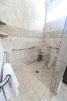 A large tiled handicap accessible shower with handrails