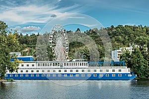 Large tourist boat with restaurant anchoring on Vltava River, ferris wheel in background, Prague, Czech republic.City excursion on