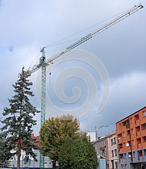 A large tower crane on a construction site against a cloudy early autumn sky .