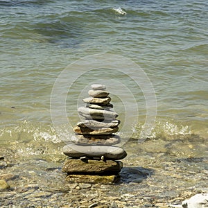 a large tower of flat stones sand pebbles on the background of the sea.