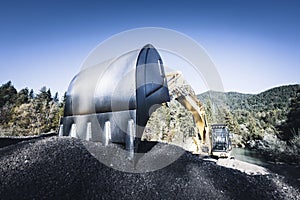 Large tracked excavator bucket in fine gravel in wooded nature