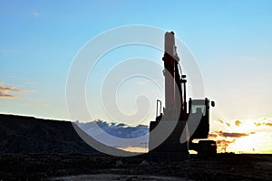 Large tracked excavator on a construction site against the background of the  awesome sunset