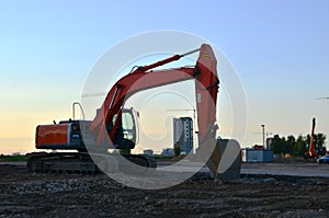 Large tracked excavator on a construction site, background of the  sunset.