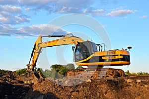 Large tracked excavator digs the ground for the foundation and construction of a new building in the city.