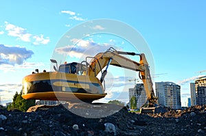 Large tracked excavator digs the ground for the foundation and construction of a new building in the city.