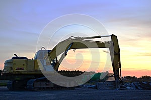 Il grande striscia escavatore idraulico martello pause asfalto sul costruzione pagine contro sul tramonto 