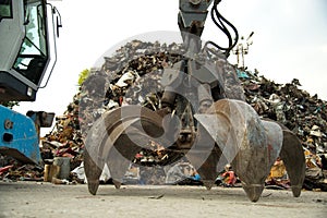 Large tracked excavator working a steel pile at a metal recycle yard. Industrial scrap metal recycling