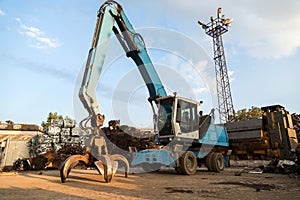 Large tracked excavator working a steel pile at a metal recycle yard. Industrial scrap metal recycling